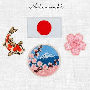 Könnte beinhalten: Ein Set aus vier bestickten Aufnähern mit dem Text Motivwahl, einer rechteckigen japanischen Flagge, einem Koi-Fisch mit orange-weißen Schuppen, einem runden Aufnäher mit Berg und Kirschblüten sowie einer einzelnen rosa Kirschblüte.