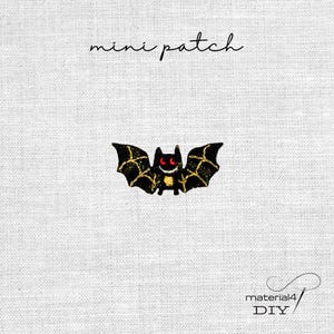 Könnte beinhalten: Ein kleiner gestickter Fledermaus-Aufnäher mit schwarzen Flügeln mit goldfarbenen Aderdetails, einer gelben Brust und leuchtend roten Augen. Der Text 'mini patch' steht darüber und 'material4 DIY' ist unten rechts abgedruckt.