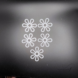 Könnte beinhalten: Fünf weiße, margeritenförmige Verzierungen mit minimalistischem Design. Die Blumen sind gleichmäßig auf einem dunkelgrauen Hintergrund verteilt. Die Blütenblätter sind abgerundet und die Zentren offen.