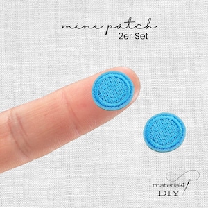Könnte beinhalten: Ein Set aus zwei kleinen, runden, hellblauen gestickten Aufnähern mit einem genähten Rand. Der Text "mini patch 2er Set" ist oben zu sehen, und der Text "material4 DIY" ist unten rechts im Bild zu sehen.