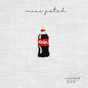 Könnte beinhalten: Ein Mini-Aufnäher mit einem gestickten Limonadenflaschen-Motiv. Die Flasche ist schwarz mit einem roten Band in der Mitte, weißem "Cola"-Schriftzug und einem weißen Verschluss. Oben steht "mini patch", unten "material4 DIY".