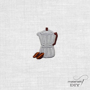 Könnte beinhalten: Gestickter Aufnäher mit einer silbernen Kaffeemaschine und zwei braunen Kaffeebohnen. Die Kaffeemaschine hat einen dunkelbraunen Griff und Deckel. Der Aufnäher befindet sich auf einem weißen Stoffhintergrund. Der Aufnäher ist ein DIY-Bastelartikel.