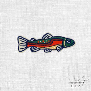 Könnte beinhalten: Ein gestickter Aufbügler in Form einer Forelle. Der Fisch hat einen dunkelgrünen Rücken, einen leuchtend orangefarbenen horizontalen Streifen entlang der Mitte und einen cremefarbenen Bauch mit kleinen orangefarbenen und weißen Punkten.