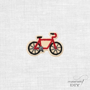 Könnte beinhalten: Ein gestickter Aufnäher, der ein rotes Fahrrad mit schwarzen Rädern und einem grauen Pedal zeigt. Das Fahrradmotiv ist mit einem cremefarbenen Rand versehen und weist detaillierte Stickereien am Rahmen sowie an den Speichen auf.