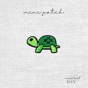 Könnte beinhalten: Ein kleiner gestickter Aufnäher, der eine grüne Schildkröte mit schwarzer Umrandung und einem Kreuzstichmuster auf dem Panzer zeigt. Der Text "mini patch" steht über der Schildkröte und "material4 DIY" steht in der unteren rechten Ecke.