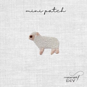 Könnte beinhalten: Ein Mini-Aufnäher mit einem gestickten Schaf in Creme- und Hellbrauntönen. Das Schaf ist im Profil nach links ausgerichtet. Der Text mini patch steht über dem Schaf und der Text material4 DIY befindet sich unten rechts im Bild.