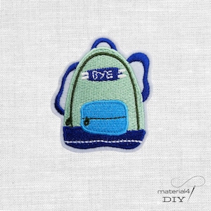 Könnte beinhalten: Gestickter Aufnäher eines Rucksacks in Grün- und Blautönen. Der Rucksack hat eine Vordertasche und das Wort "BYE" ist oben aufgestickt. Der Aufnäher befindet sich auf einem weißen Stoffhintergrund.