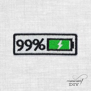 Könnte beinhalten: Gestickter Aufnäher mit einem Akkusymbol bei 99 % Ladung. Der rechteckige Aufnäher hat einen schwarzen Rand mit der Zahl "99%" in schwarzem Text. Die Batterieanzeige ist grün mit einem weißen Blitzsymbol.