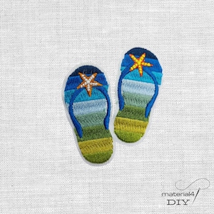 Könnte beinhalten: Gestickte Aufnäher von zwei Flip-Flops. Die Flip-Flops haben einen blauen Riemen und ein Farbverlaufdesign aus Blau, Grün und Gelb. Jeder Flip-Flop hat einen orangefarbenen Seestern. Die Aufnäher befinden sich auf weißem Hintergrund.