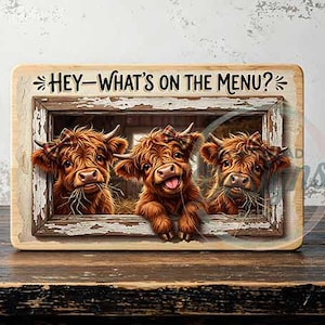 Könnte beinhalten: Holzschild mit drei Highland-Rindern, die durch einen rustikalen Fensterrahmen schauen. Die Kühe haben braunes Fell und karierte Schleifen. Auf dem Schild steht "HEY - WHAT'S ON THE MENU?" in schwarzer Schrift. Der Hintergrund ist verwittert.