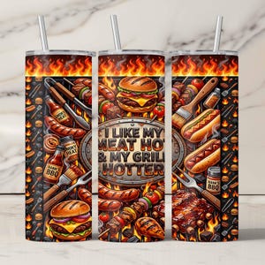 Könnte beinhalten: Ein Edelstahlbecher mit Grill-Motiv. Das Design zeigt Bilder von gegrilltem Essen, Flammen und den Text "I LIKE MY MEAT HOT & MY GRILL HOTTER". Enthält einen silbernen Strohhalm.