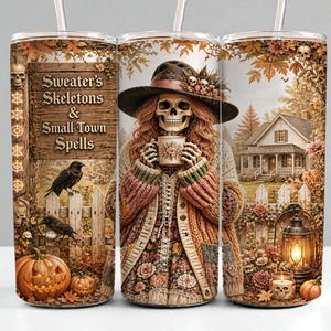 Könnte beinhalten: Ein zylindrischer Becher mit einem Grafikdruck eines Skeletts, das einen Hut und eine Strickjacke trägt und eine Tasse hält. Das Design umfasst ein Holzschild mit dem Text Sweater's Skeletons & Small Town Spells, Kürbisse, Krähen und ein Haus.
