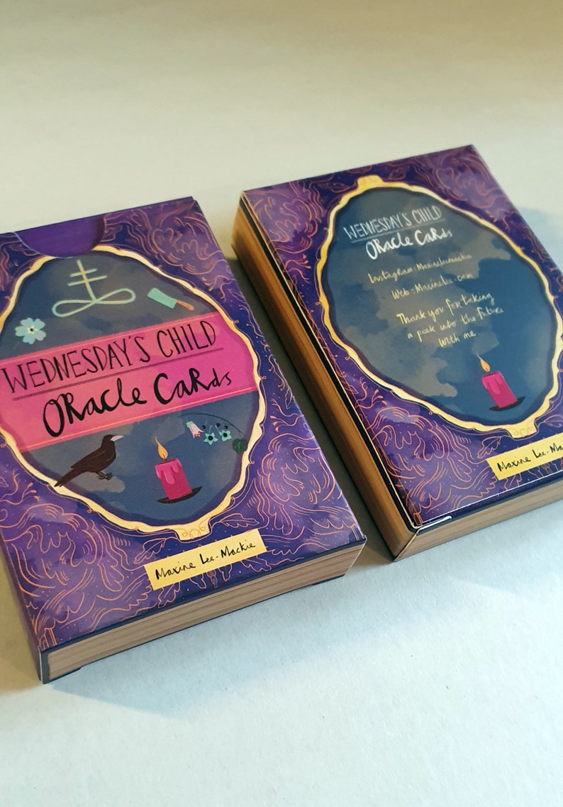 May include: Two boxes of Wednesday's Child Oracle Cards. The boxes are purple with gold accents and feature a black crow, a lit candle, and a pentagram. The text on the boxes reads "Wednesday's Child Oracle Cards" and "Maxine Lee-Mackie".