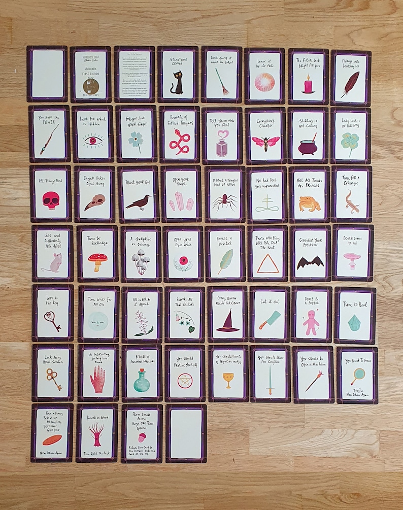 May include: A set of 48 tarot cards with colorful illustrations and text on each card. The cards are arranged in a grid pattern on a wooden surface. The cards feature a variety of images, including animals, plants, and objects. The text on the cards is in a handwritten style.