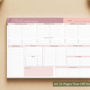 Op de afbeelding: Een rechthoekig A4 weekplanner-blok met 52 afscheurbare pagina's. De planner heeft een mauve en lichtroze koptekst met de tekst Weekly Brain Dump en Week. Het bevat secties voor dagelijkse taken, een to-do lijst en huishoudelijke notities.