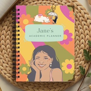 May include: A spiral-bound academic planner featuring a colourful background with wavy stripes and flowers. The cover displays the text Jane's ACADEMIC PLANNER in a light green box, an illustration of a person, and a small cat with an umbrella charm.