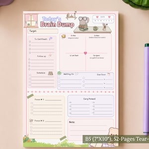 以下が含まれることがあります： Today's Brain Dumpと書かれたB5サイズ（17.78cm x 25.4cm）の52ページ綴りのメモ帳。目標、電話、フォローアップ、スケジュール、フォーカス、持ち越し、メモ用のセクションがあり、机や本、クマのイラストが描かれています。