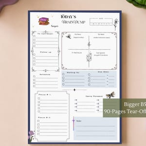 Op de afbeelding: Een B5 afscheurblok met 90 pagina's, getiteld Today's Brain Dump. De lay-out bevat secties voor bellen/e-mailen, opvolging, planning, focus en een prioriteitenmatrix. Het bevat illustraties van boeken, een vlinder en een zwaard.