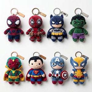 Könnte beinhalten: Ein Set aus acht gehäkelten Plüsch-Schlüsselanhängern mit verschiedenen Superhelden-Figuren wie Spider-Man, Deadpool, Batman, Hulk, Vision, Superman, Captain America und Wolverine, jeweils an einem silberfarbenen Metallring mit einem kleinen Anhänger.