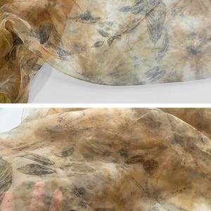 May include: A sheer fabric with a brown and beige background and a leaf pattern printed on it. The fabric is translucent and has a soft, flowing texture.