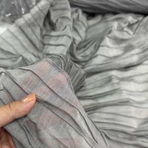 Könnte beinhalten: Grauer plissierter Stoff mit weicher, seidenartiger Textur. Der Stoff ist leicht und fällt wunderschön.