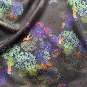 May include: Dark grey fabric with a floral pattern of blue, purple, and green hydrangeas. The fabric has a subtle sheen and a detailed design, with hints of orange and pink.