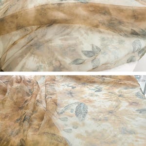 May include: A sheer fabric with a brown and white background and a leaf pattern. The fabric is translucent and has a soft, flowing texture.