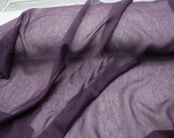 May include: A sheer, deep purple fabric featuring a delicate, crinkled texture throughout. The material is translucent and lightweight, with folds creating varying depths of color and shadow across the surface of the draped textile.