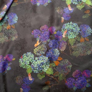 May include: Dark fabric with a floral pattern of blue, purple, and green hydrangeas. The design includes orange butterflies and green leaves against a dark background. The fabric has a subtle sheen.