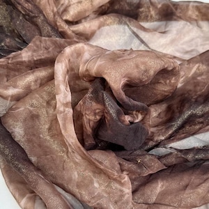 Könnte beinhalten: Ein schimmernder brauner und goldener Schal mit Marmorierung. Der Schal ist aus einem leichten Stoff gefertigt und hat einen weichen, fließenden Fall.