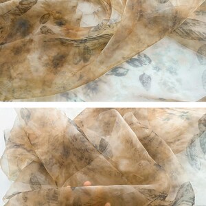 May include: A sheer, brown fabric with a delicate leaf pattern. The fabric is translucent and has a soft, flowing texture.
