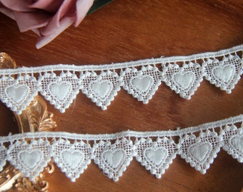 May include: White lace trim with a scalloped edge and a repeating heart design.