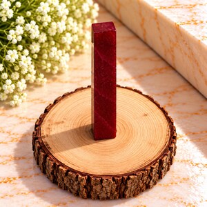 May include: A tall, rectangular, deep red wax seal stamp with a subtle diagonal texture, standing upright on a circular wooden slice base with visible bark edges. The wax seal features a smooth, polished finish and a consistent, rich crimson colour.