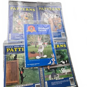 Peut inclure: Un ensemble de cinq paquets de modèles de menuiserie emballés dans du plastique, présentant des illustrations de personnages Looney Tunes, de chats et de chiens. Chaque paquet affiche des designs de projets en taille réelle, incluant Dog & Cat Yard Shadow et Lazy Cats, avec du texte imprimé et des codes-barres sur les couvertures.