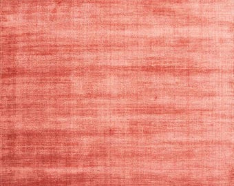 Puede incluir: Una alfombra rectangular de color coral con un patrón horizontal texturizado. La superficie de la alfombra tiene un aspecto suave y afelpado, con variaciones de color que crean un efecto sutil y envejecido. La alfombra es adecuada para salones, dormitorios o entradas.