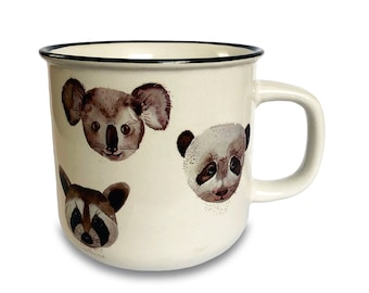 Può includere: Tazza in ceramica bianca con bordo e manico neri. La tazza presenta illustrazioni di un koala, un panda e un procione.