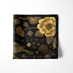 May include: Black pocket square with a gold floral and bird design. The square features a large gold flower, leaves, and a bird, all set against a black background. The edges are neatly finished.