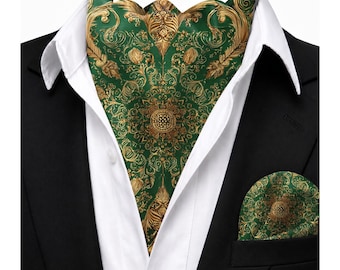 Puede incluir: Un pañuelo de cuello verde y dorado con un intrincado patrón simétrico de volutas, usado con una camisa blanca de cuello y un blazer negro. Un pañuelo de bolsillo a juego verde y dorado con un motivo central circular está en el bolsillo.