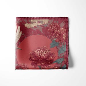 May include: A square, burgundy pocket square with a floral design. The design features large, burgundy flowers, a red sun, and a light-colored cloud pattern. The edges are a darker burgundy.