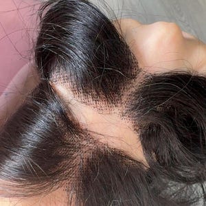 May include: A dark brown lace front wig with a natural hairline. The wig features long, flowing hair and is designed to blend seamlessly with the wearer's skin. The lace is visible, indicating the wig's construction.