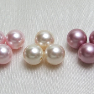 May include: A collection of pearl beads in three colors: pink, light pink, and white. The beads are arranged in three groups of three.