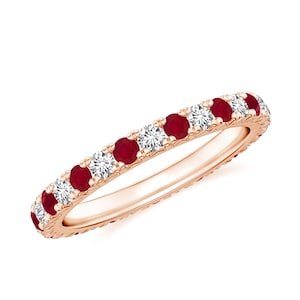 May include: Rose gold eternity ring featuring alternating round-cut rubies and diamonds. The gemstones are set in a continuous row around the band. The ring is displayed against a white background.