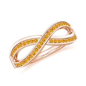 May include: Rose gold infinity ring with a double band design. The ring is encrusted with small, round, yellow gemstones. The gemstones are set along the top and bottom edges of the infinity symbol.