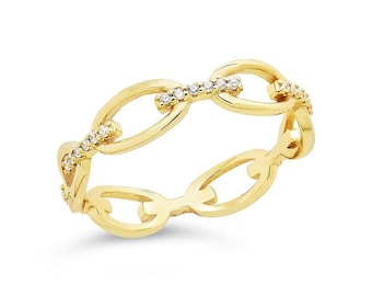 May include: A gold-colored chain link ring with small, clear gemstones set along the links. The ring is made of a shiny, polished metal and is set against a white background. The ring's design is a continuous chain link pattern.