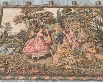 May include: A rectangular woven wall tapestry featuring a pastoral scene with figures in period clothing dancing and relaxing near a stone fountain. The landscape includes lush trees, a river with a swan, and a decorative border with leaf motifs.
