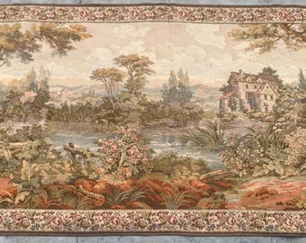 May include: A large rectangular tapestry featuring a pastoral landscape scene. The tapestry depicts a river, trees, and a building, with a decorative floral border. The color palette includes shades of brown, beige, and green.