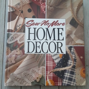 May include: A book titled "Sew-No-More HOME DECOR" with a collage of fabric swatches on the cover. The fabrics are in various patterns and colors, including red, white, blue, and brown.