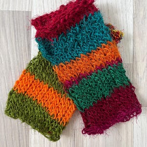 May include: A pair of fingerless gloves featuring a textured, open-knit construction with horizontal stripes in vibrant shades of deep red, teal, bright orange, forest green, and magenta. The yarn has a fuzzy, slightly frayed appearance.