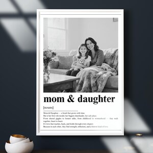 May include: Black and white framed print with the words "mom & daughter" and a definition. The image shows a mother and daughter on a couch. The definition describes the bond between a mother and daughter.