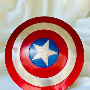 May include: A red, white, and blue Captain America shield. The shield has a red outer ring, a silver middle ring, and a blue center with a white star. This shield is a popular item for cosplay and superhero enthusiasts.